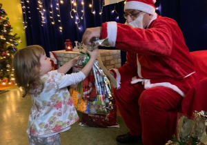 Dziewczynka odbiera prezent od Świętego Mikołaja