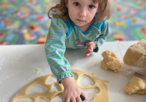 Dziewczynka wycina ciasteczka z formy w kształcie serca