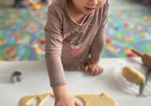 Dziewczynka wycina ciasteczka z formy w kształcie serca