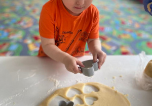 Chłopczyk wycina ciasteczka z formy w kształcie serca