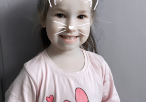 Dziewczynka z filtrem - maską kota uśmiecha się do zdjęcia