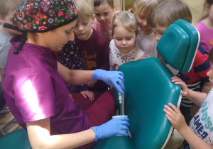 dentysta pokazuje dzieciom sprzęt przydatny w swojej pracy