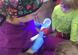 dentysta pokazuje jak zakłada się plombę na modelu szczęki