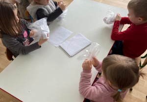 Dzieci w sali przy stolikach wykonują pracę plastyczną "Ząbek"