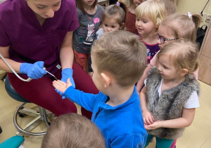 Stomatolog pokazuje dzieciom jak wygląda przyrząd ze sprężonym powietrzem