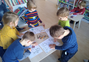 dzieci kolorują obrazki przy stolikach
