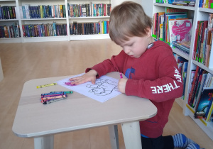 chłopiec koloruje obrazek przy stoliku