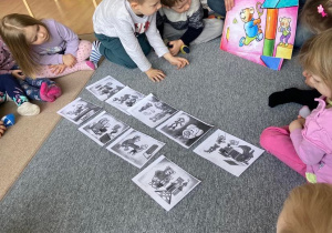 Dzieci układają historyjkę obrazkową do czytanej książki na dywanie