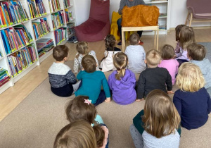 Dzieci na dywanie słuchają czytanej książki