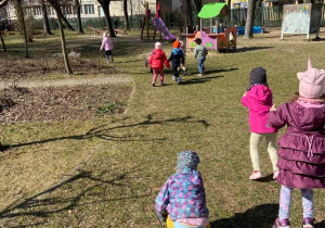 Dzieci w ogrodzie przedszkolnym skaczą i udają żaby