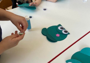 Dzieci przy stoliku wykonują prace plastyczną - żabę