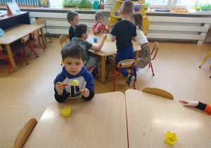 Sala przedszkolna. Dzieci siedzą przy stole i malują jajka ze styropianu.