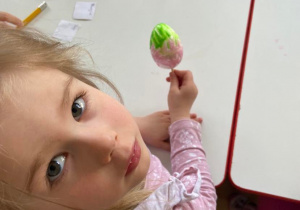 Dziewczynka pokazuje do zdjęcia pomalowane styropianowe jajko