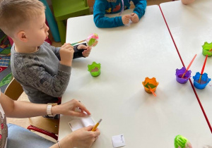 Dzieci przy stoliku malują styropianowe jajka farbami