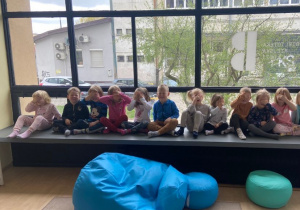 Dzieci siedzą w siadzie skrzyżnym i zakrywają oczy