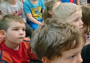 Sala gimnastyczna w przedszkolu. Dzieci siedą na widowni. Z uwagą słuchają wierszy recytowanych przez Eugeniusza Dolata.