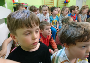 Sala gimnastyczna w przedszkolu. Dzieci siedą na widowni. Z uwagą słuchają wierszy recytowanych przez Eugeniusza Dolata.