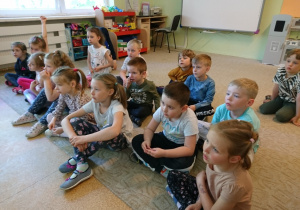 Sala przedszkolna. Dzieci siedzą na dywanie i z zaciekawieniem słuchają opowieści Strażaka.