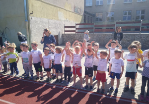 dzieci rozgrzewają się do biegu poprzez wykonywanie ćwiczeń gimnastycznych