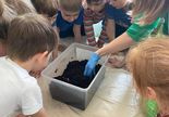 dzieci przygotowują kompostownik w plastikowym pojemniku