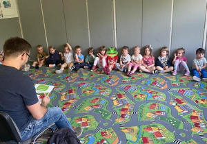 Dzieci na dywanie słuchają czytanej książki przez Tatę dziewczynki z grupy