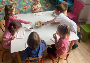 Dzieci spożywają chrupki przy stoliku