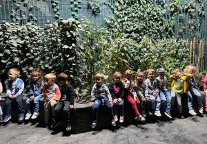 Dzieci siedzące pod bluszczową ścianą