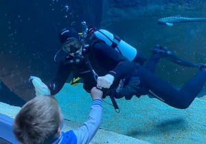Chłopiec przykładający rękę do akwarium w którym pływa nurek