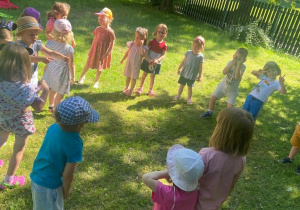 Dzieci tańczą w kole w ogrodzie