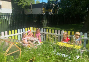 Dzieci w oddzielonym ogródku z grządkami pozują do zdjęcia