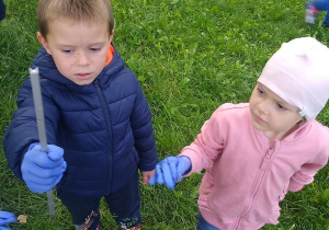 dziewczynka i chłopiec pokazują znalezione przez siebie śmieci