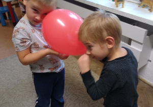 dzieci tańczą w parach z balonami trzymając je między głowami