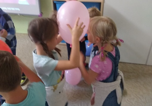 dzieci tańczą w parach z balonami trzymając je między głowami