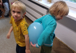dzieci tańczą z balonami trzymając je pomiędzy swoimi plecami