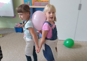 dzieci tańczą z balonami trzymając je pomiędzy swoimi plecami