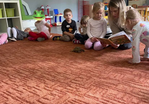 Dzieci na dywanie słuchają książki czytanej przez jedną z Mam, na dywanie żółw