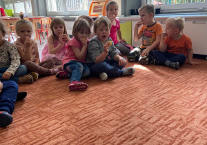 Dzieci na dywanie zjadają jabłka