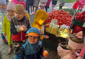Dzieci w kolejce do kasy z wybranymi jabłkami w dłoni