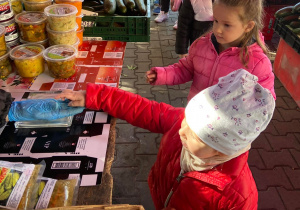 Dziewczynka kupująca jabłko na okolicznym ryneczku