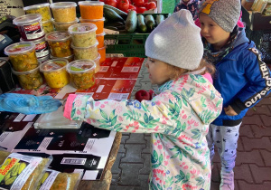 Dziewczynka kupująca jabłko na okolicznym ryneczku