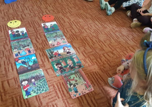 Dziewczynka układa na dywanie obrazek przedstawiający prawidłowe, ekologiczne zachowanie.