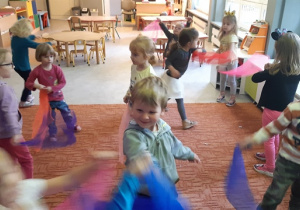 Dzieci bawią się, tańczą z kolorowymi chustkami.