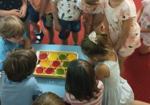 Sala przedszkolna.Dzieci nalewają do skórek po owocach kolorowe galaretki.