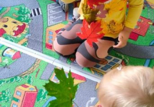 Dzieci oglądają jesienne liście. Dziewczynka pokazuje swój kolorowy listek