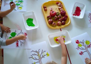 Dzieci stemplują połówkami jabłek umaczanymi w farbie