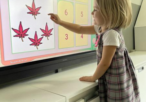 dziewczynka rozwiązuje zadanie matematyczne na ekranie multimedialnym