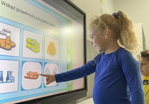 dziewczynka rozwiązuje zadanie na ekranie multimedialnym