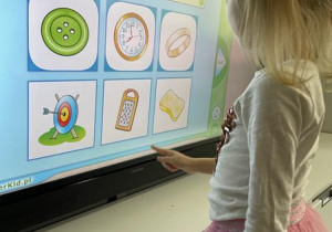 dziewczynka rozwiązuje zadanie na ekranie multimedialnym