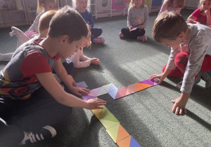 dzieci na dywanie układają domino z odcieniami różnych kolorów