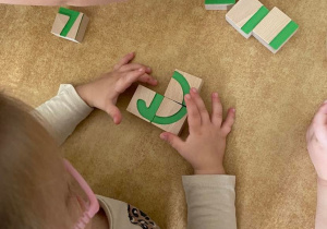 Dziewczynka układa wzór literki A z drewnianych klocków
